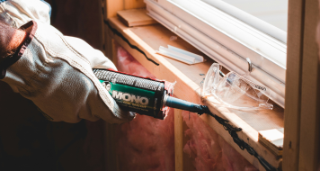 Home improvement contractor applying sealant during a window installation.